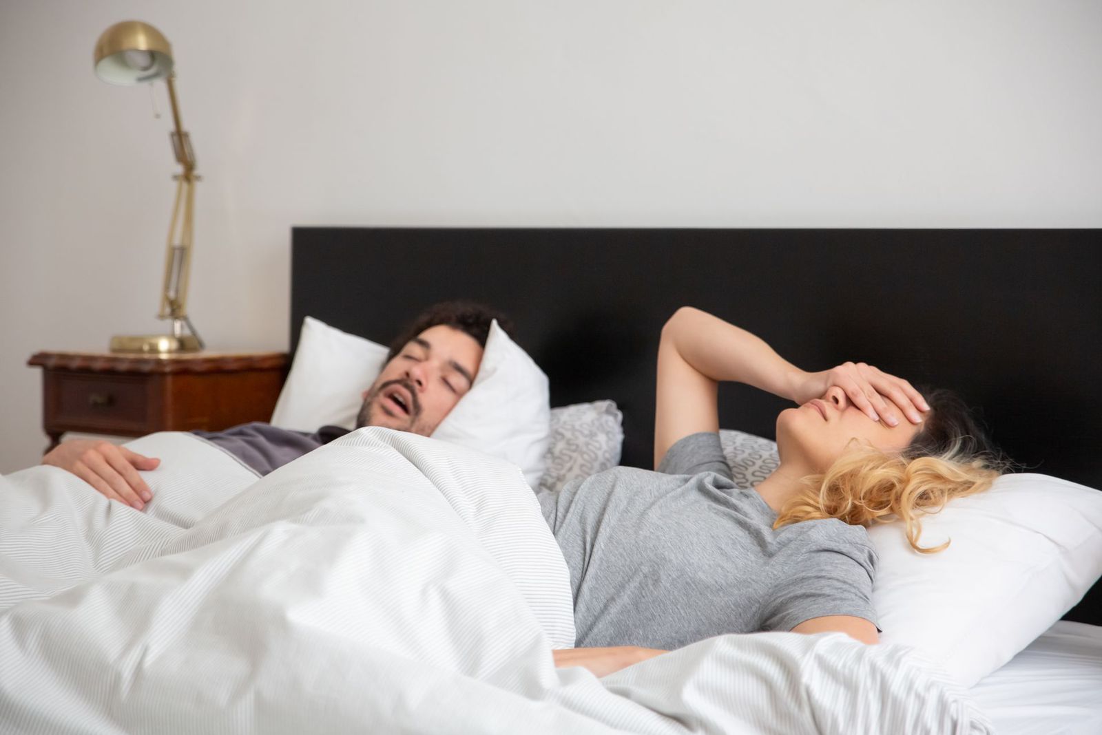 Casal na cama: homem roncando e mulher sem conseguir dormir